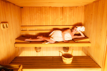 Obraz na płótnie Canvas woman lying relaxed in wooden sauna