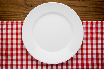 Empty white plate on wooden over red grunge background