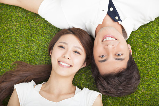 Top view of young couple in love lying together on the grass