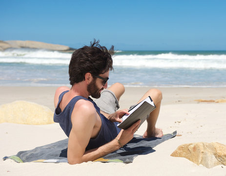 Young Man Reading Book On Secluded Beach