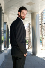 Fototapeta premium Male fashion model in black business suit standing outdoors