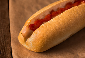 Hot dog with ketchup on wooden background
