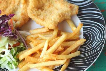 Steaks, french fries with vegetables salad on a plate.