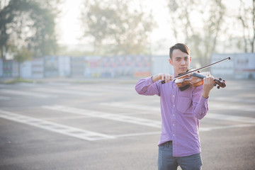 Young man playing violin outdoors