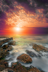Obrazy na Plexi  Skały, morze, krwawy zachód słońca.