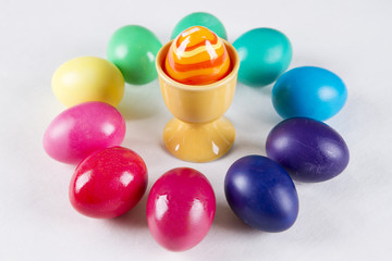Colored eggs in a cup on a white background
