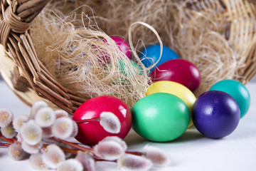 Fototapeta na wymiar Wicker basket with colored eggs and willow branches