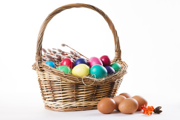 Wicker basket with colored eggs and willow branches