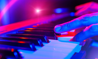 hands of musician playing keyboard in concert with shallow depth