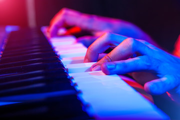 hands of musician playing keyboard in concert with shallow depth