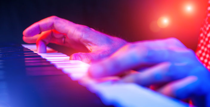 hands of musician playing keyboard in concert with shallow depth