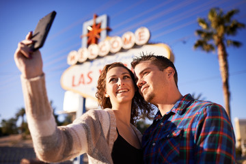 romantic couple taking selfie in front of las vegas sign