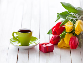 Cup and gift box with bouquet of tulips