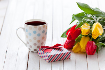 Cup and gift box with bouquet of tulips