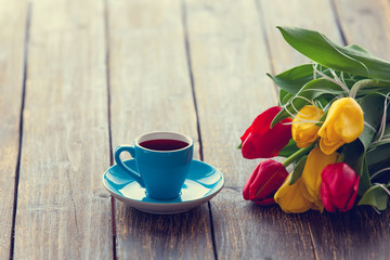 Fototapeta na wymiar Cup of coffee and bouquet of tulips