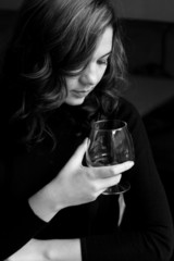 Beautiful young curly brunette holding a glass with alcohol