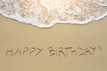 happy birthday written on sand beach