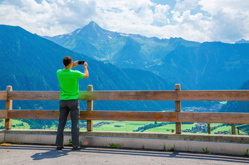 Fototapeta na wymiar Young tourist taking a photo of alpine landscape, Austria