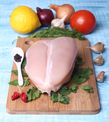 raw chicken breast and vegetables on a cutting Board