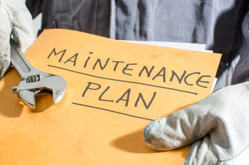 Worker holding a folder of maintenance plan and monkey wrench