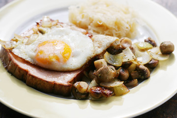 Leberkäse mit Ei, Zwiebeln und Pilzen, deftiges Essen nach traditioneller Art in Bayern, rustikal und fettig