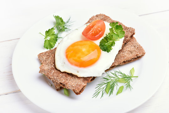 Crispbread with egg, tomato slice and herbs