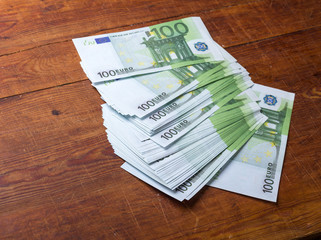Close-up of 100 Euro banknotes on wood background.