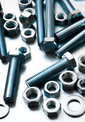 Nuts, washers and bolts on scratched metal background.
