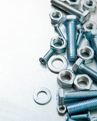 Nuts, washers and bolts on scratched metal background.