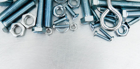 Nuts, screws and bolts on scratched metal background.