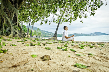 Man doing meditation exercises on the beach