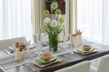 table set on wooden dinning table with flower in glass vase