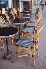Fototapeta na wymiar Round tables and wicker chairs in a cafe in Paris, France.