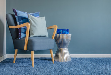 wooden chair with blue color pillow on carpet