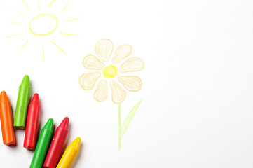 Oil pastel crayons lying on a paper with painted flower and sun