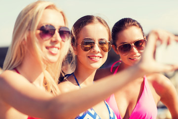 group of smiling women making selfie on beach