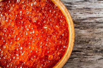 fresh red caviar in a wooden bowl closeup