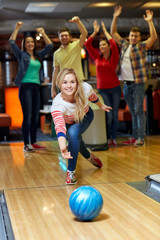 happy young woman throwing ball in bowling club
