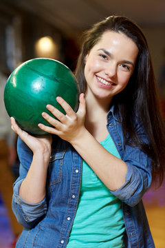 happy young woman holding ball in bowling club