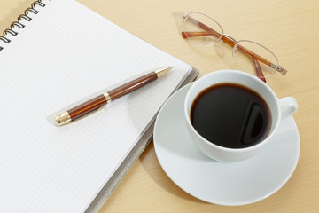 Image of notebook, coffee cup, pen and glasses