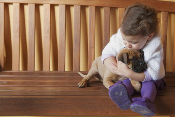 Children girl kissing and hugging her dog puppy