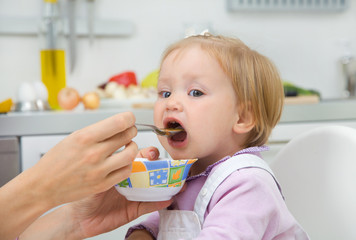mother feeding baby in the kitchen