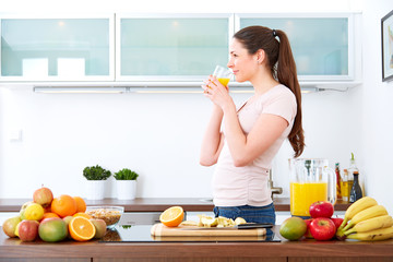 Young woman drinking a glass of orange Juice in the kitchen.