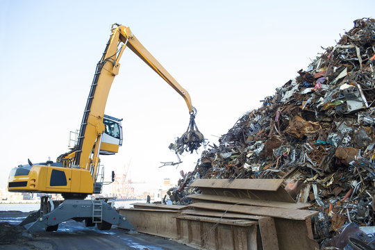 Large tracked excavator working a steel pile at a metal recycle