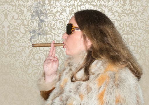 Frau mit Pelzmantel und Sonnenbrille raucht eine Zigarre
