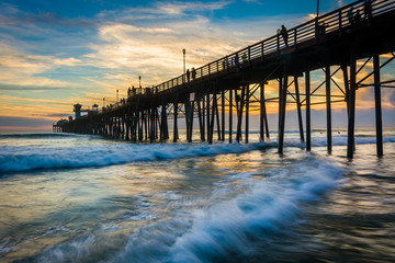 The pier and waves in the Pacific Ocean at sunset, in Oceanside,