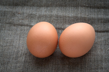 Two chicken eggs on hessian linen fabric cloth texture