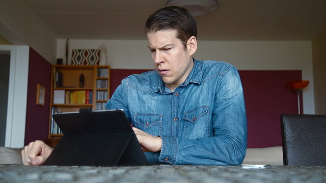 man at home with tablet and bad news