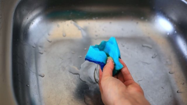 hands with sponge washing dishes impregnated With detergent in