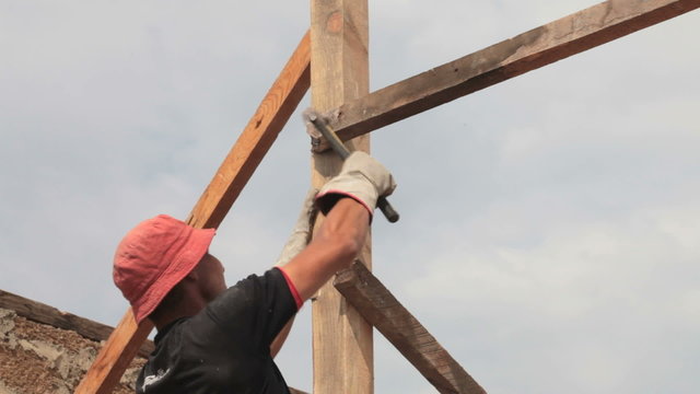 roofer nailing wood board with hammer on roof installation work